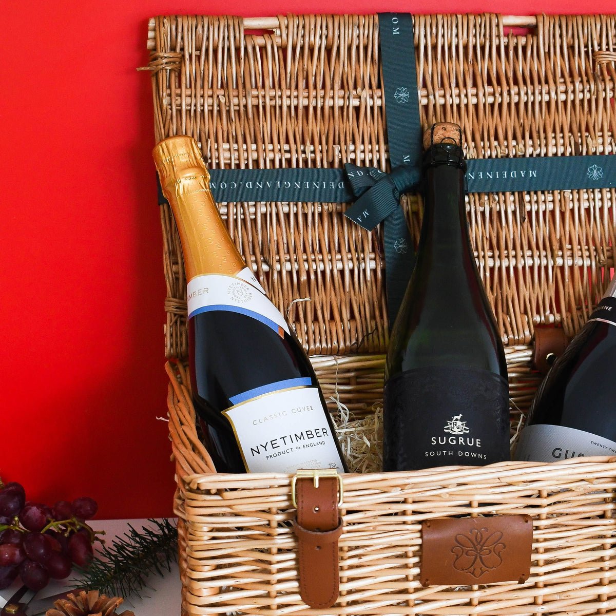 Three bottles of English sparkling wine in a wicker Christmas hamper