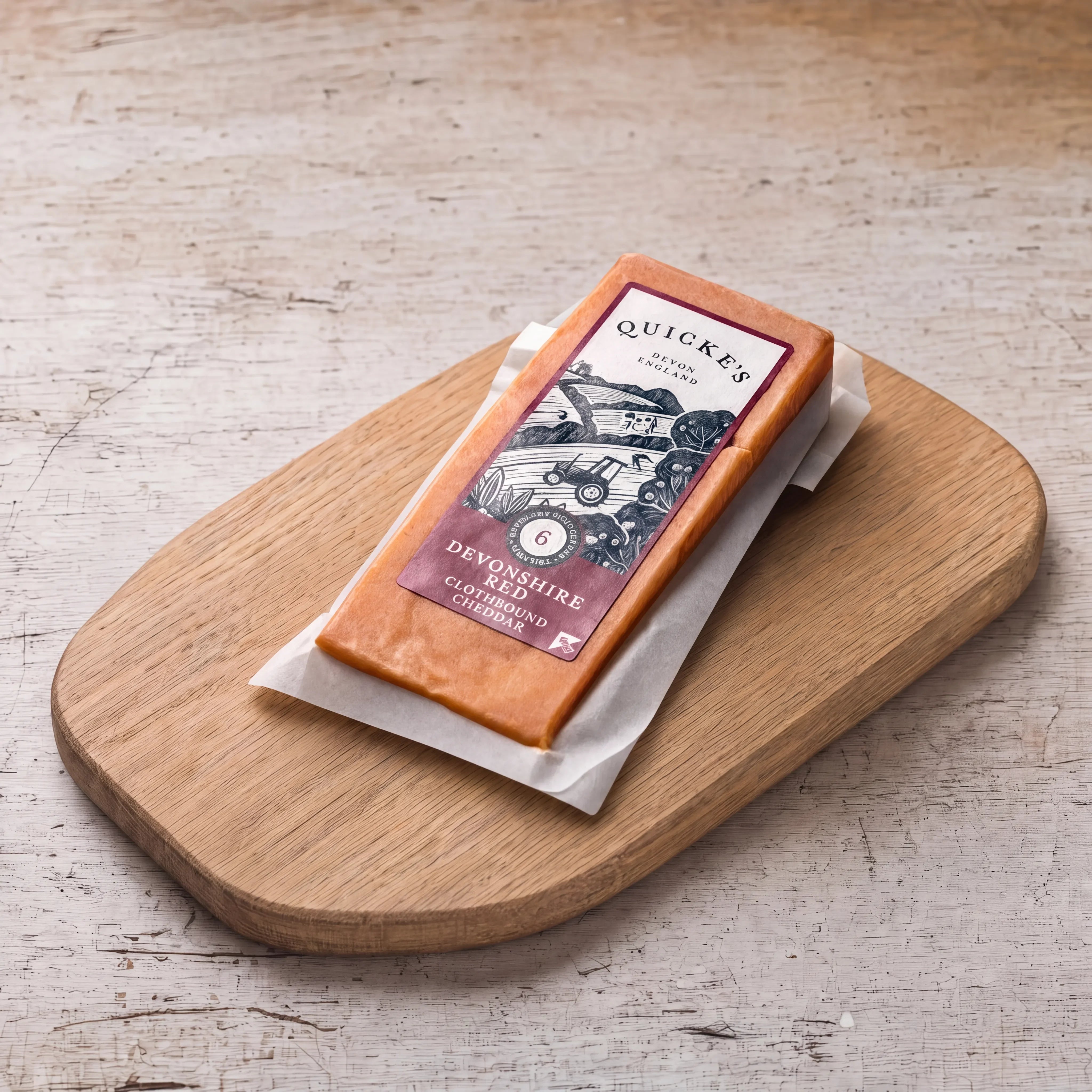 Quicke's Devonshire Red Clothbound Cheddar on an oak board, English cheesemonger counter