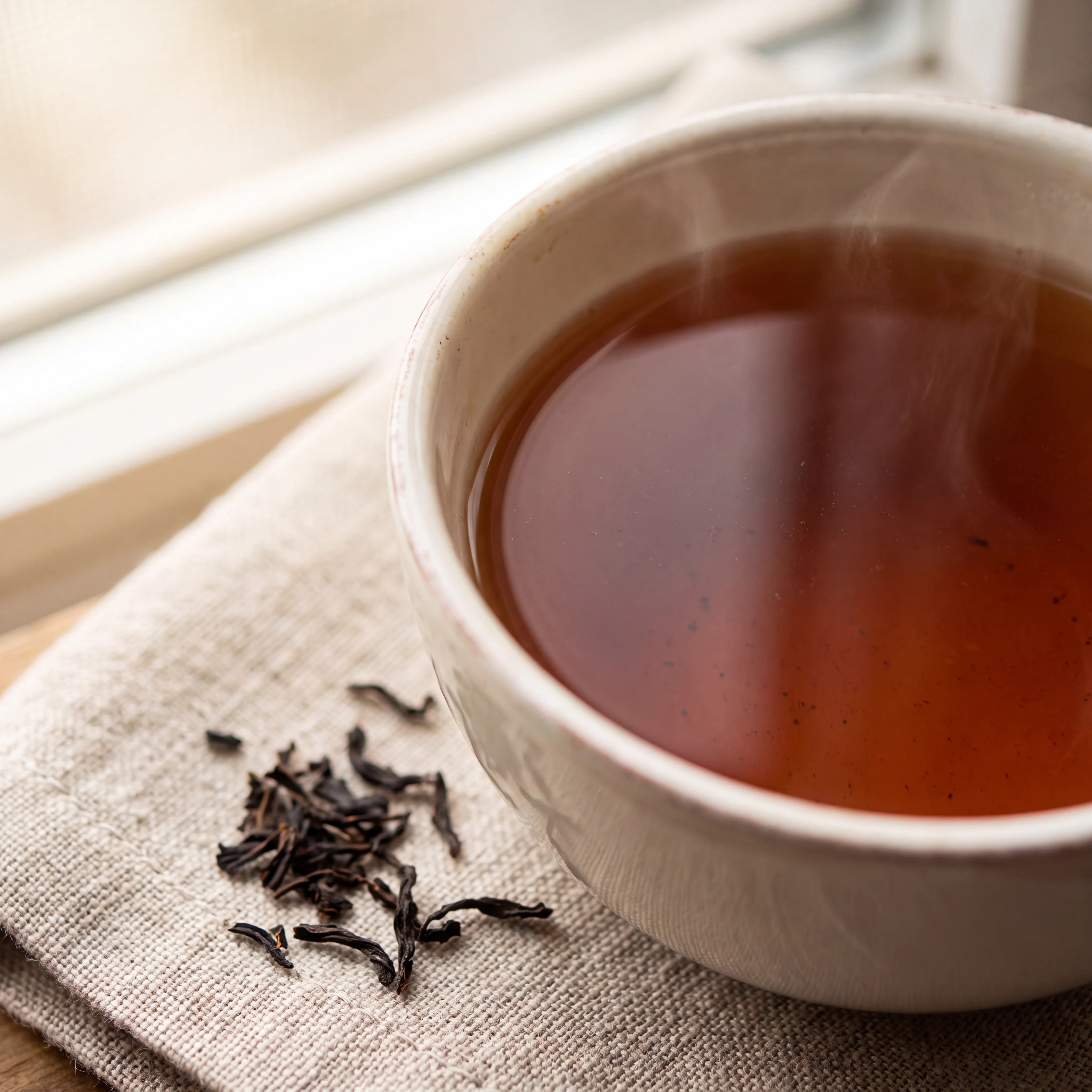 Cup of amber English Breakfast tea with loose black tea leaves