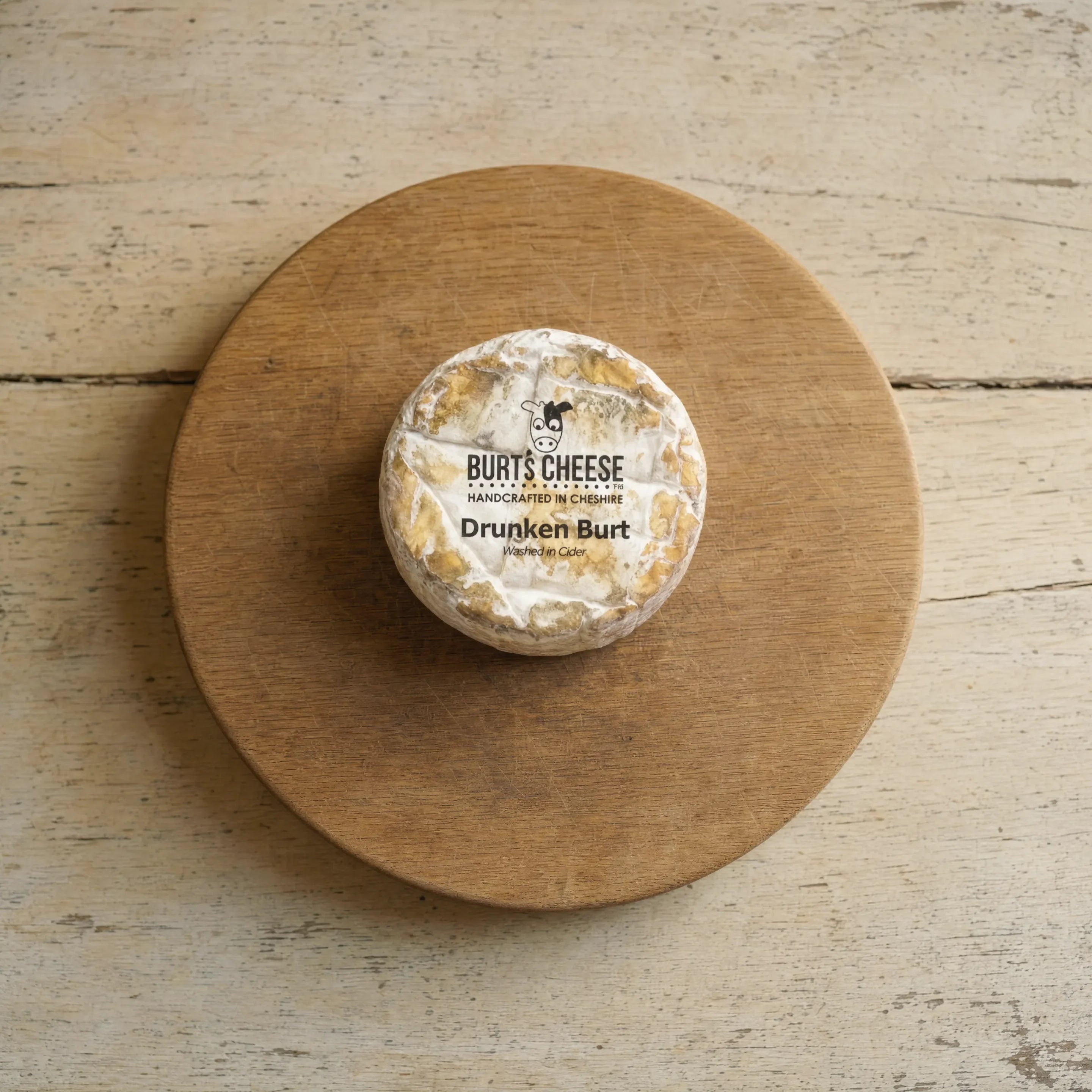 Drunken Burt cider-washed cheese on an oak board, English cheesemonger counter