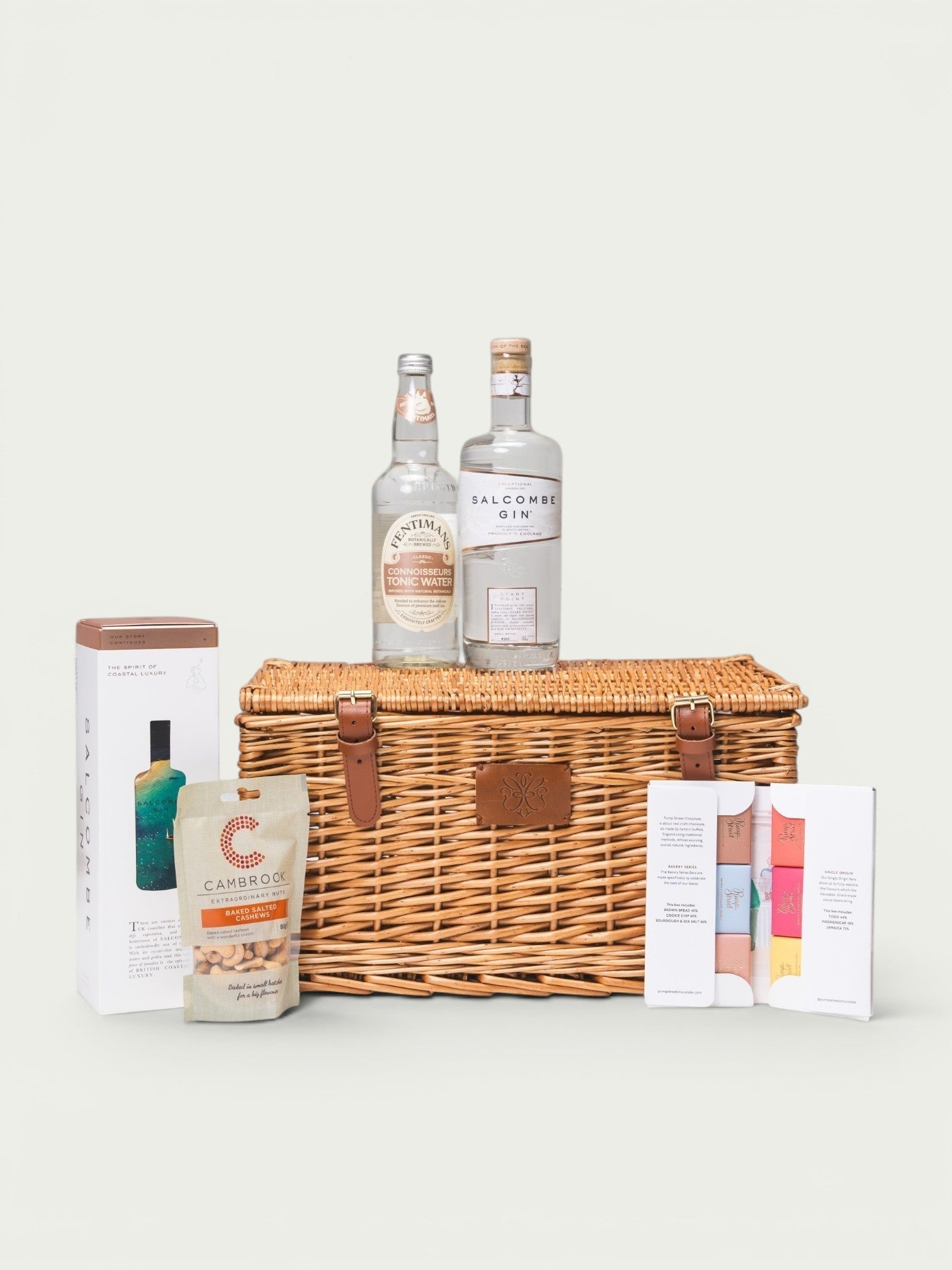 Made In England Gin And Tonic Hamper with Salcombe Gin, Fentimans Tonic, cashews, and chocolate bars in a wicker basket.