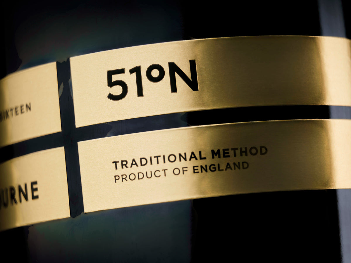 Close-up of Made In England Gusbourne 51°N sparkling wine bottle with elegant gold label and black lettering.