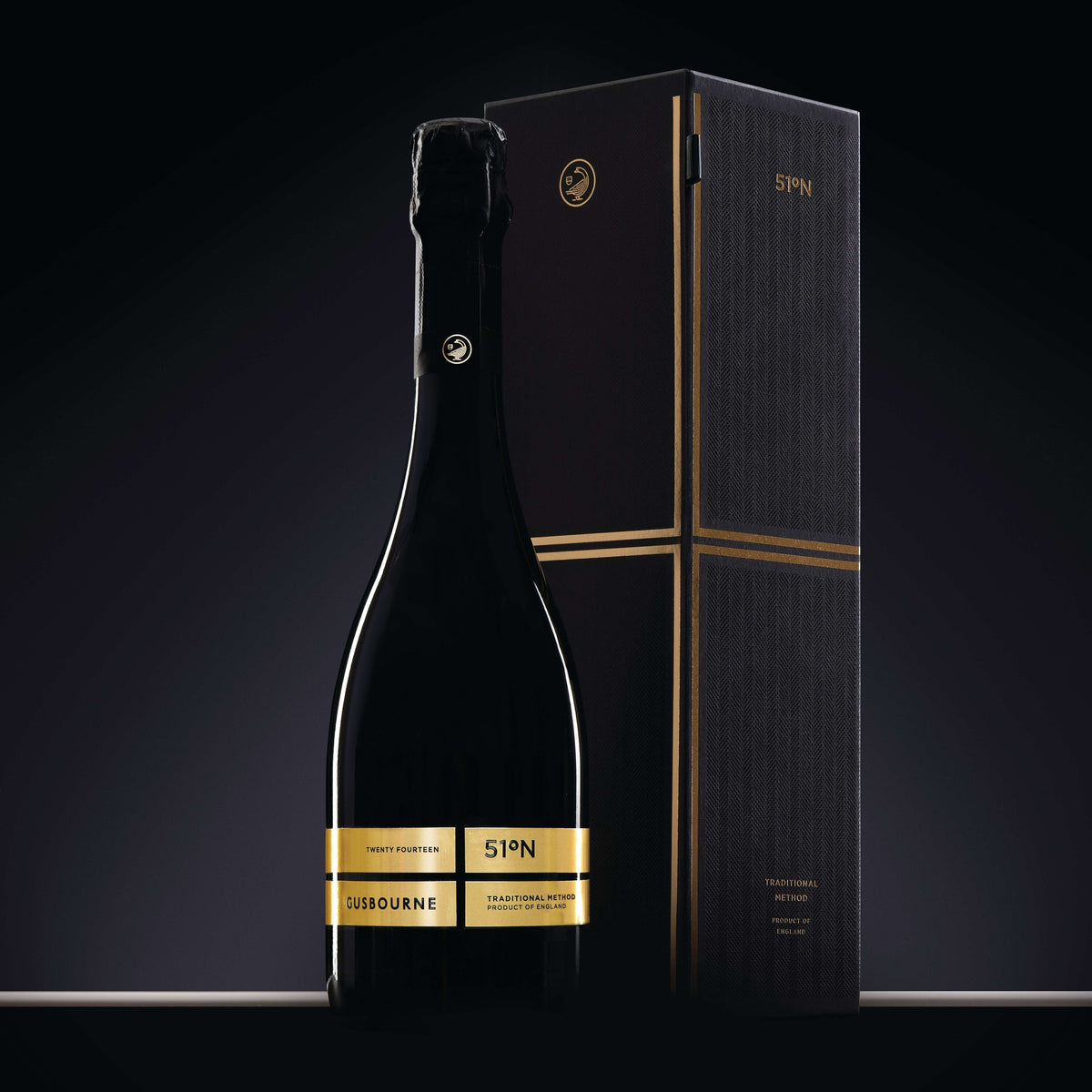 Made In England Gusbourne 51°N sparkling wine bottle with gold label and matching presentation box on black background.