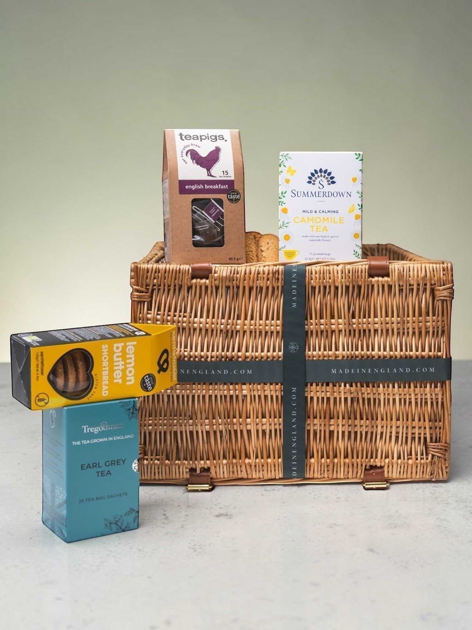 Made In England tea and biscuit gift hamper in a wicker basket with Teapigs English Breakfast, Summerdown Camomile, Tregothnan Earl Grey tea, and lemon butter shortbread.