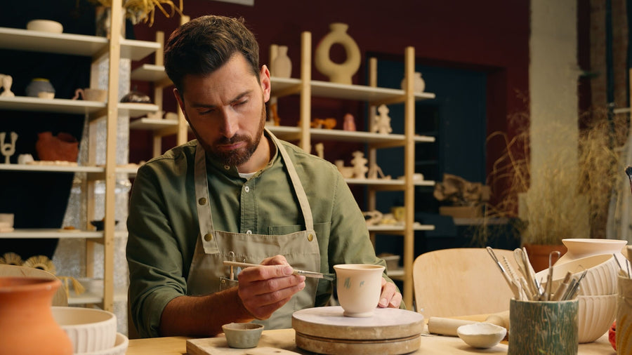 A potter painting a cup in his workshop