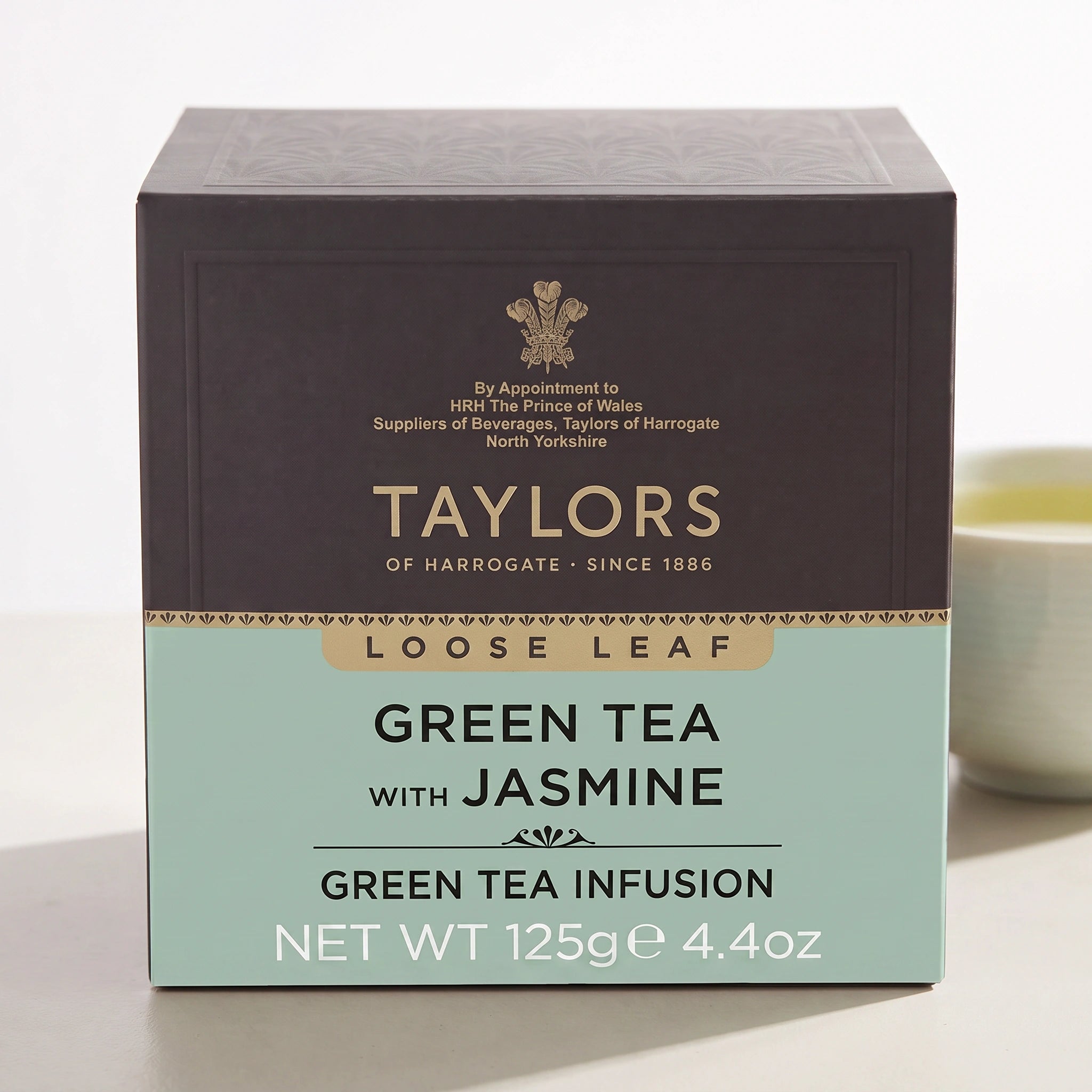 Taylors Green Tea with Jasmine pack front-on with a cup of green tea