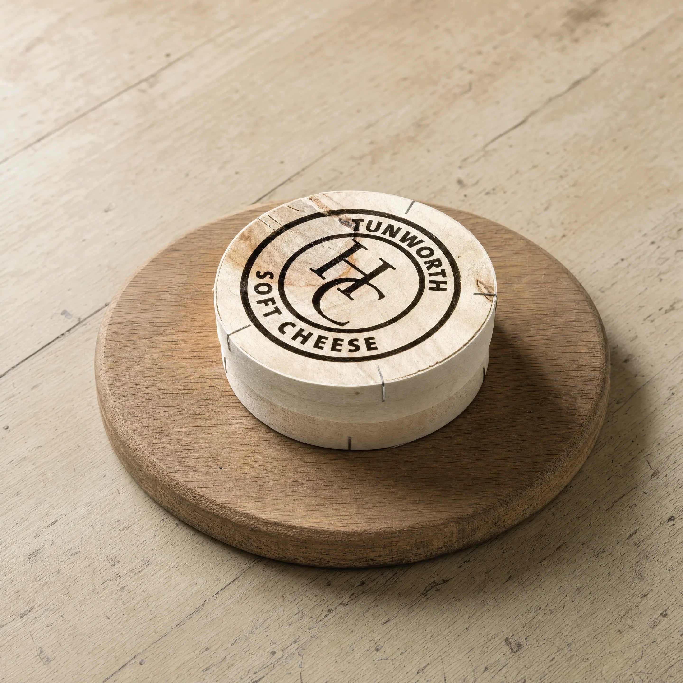 Tunworth soft cheese in branded box on a cheese board, English cheesemonger counter