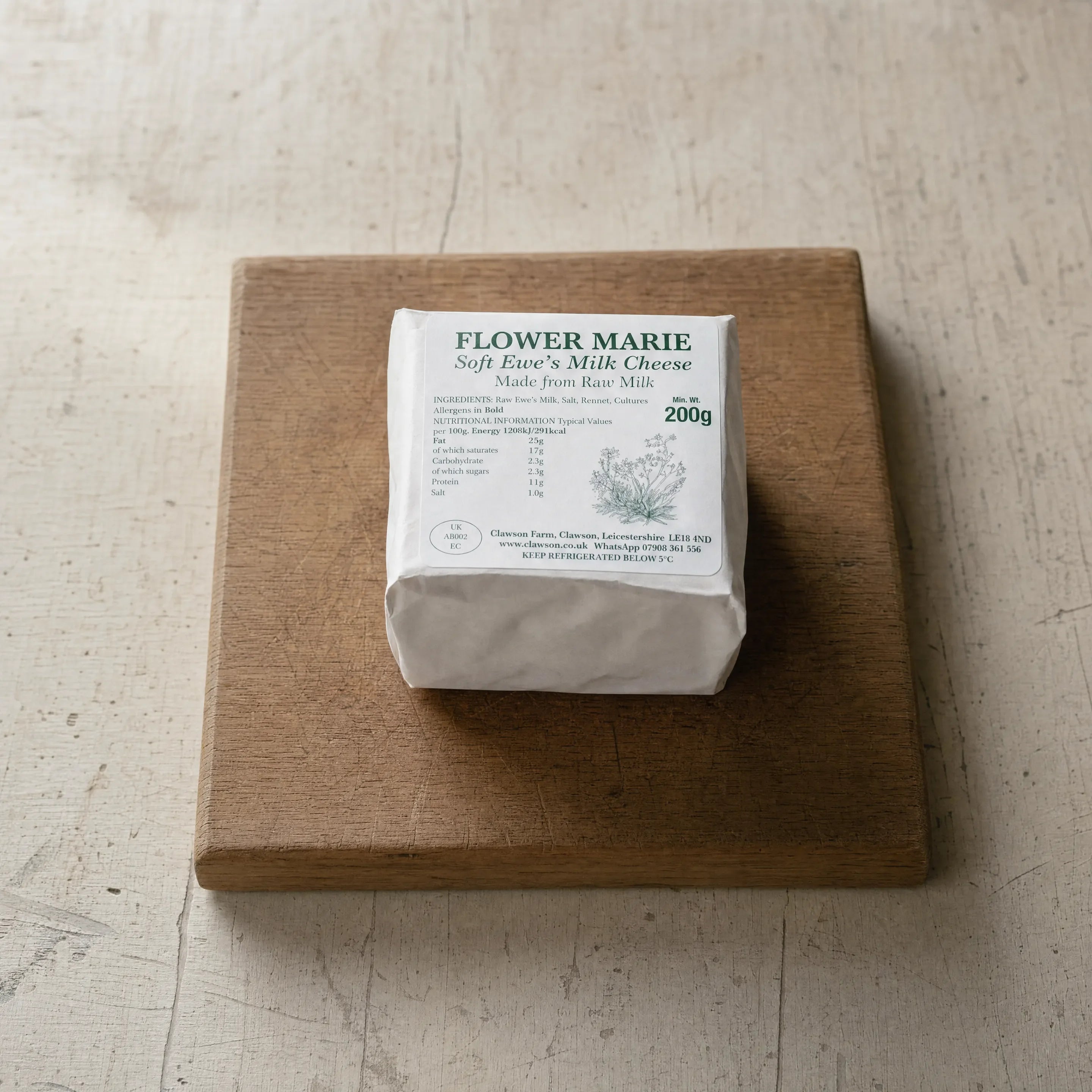 Flower Marie ewes' milk cheese on an oak board, English cheesemonger counter