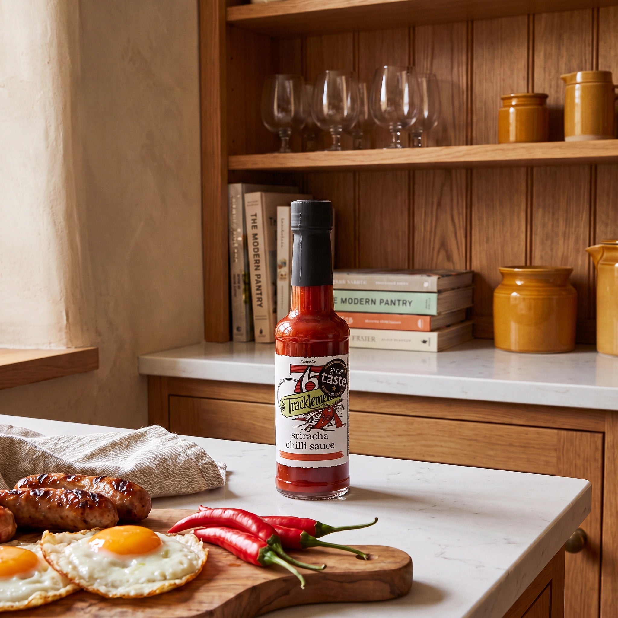 Tracklements Sriracha Chilli Sauce bottle in a rustic kitchen setting