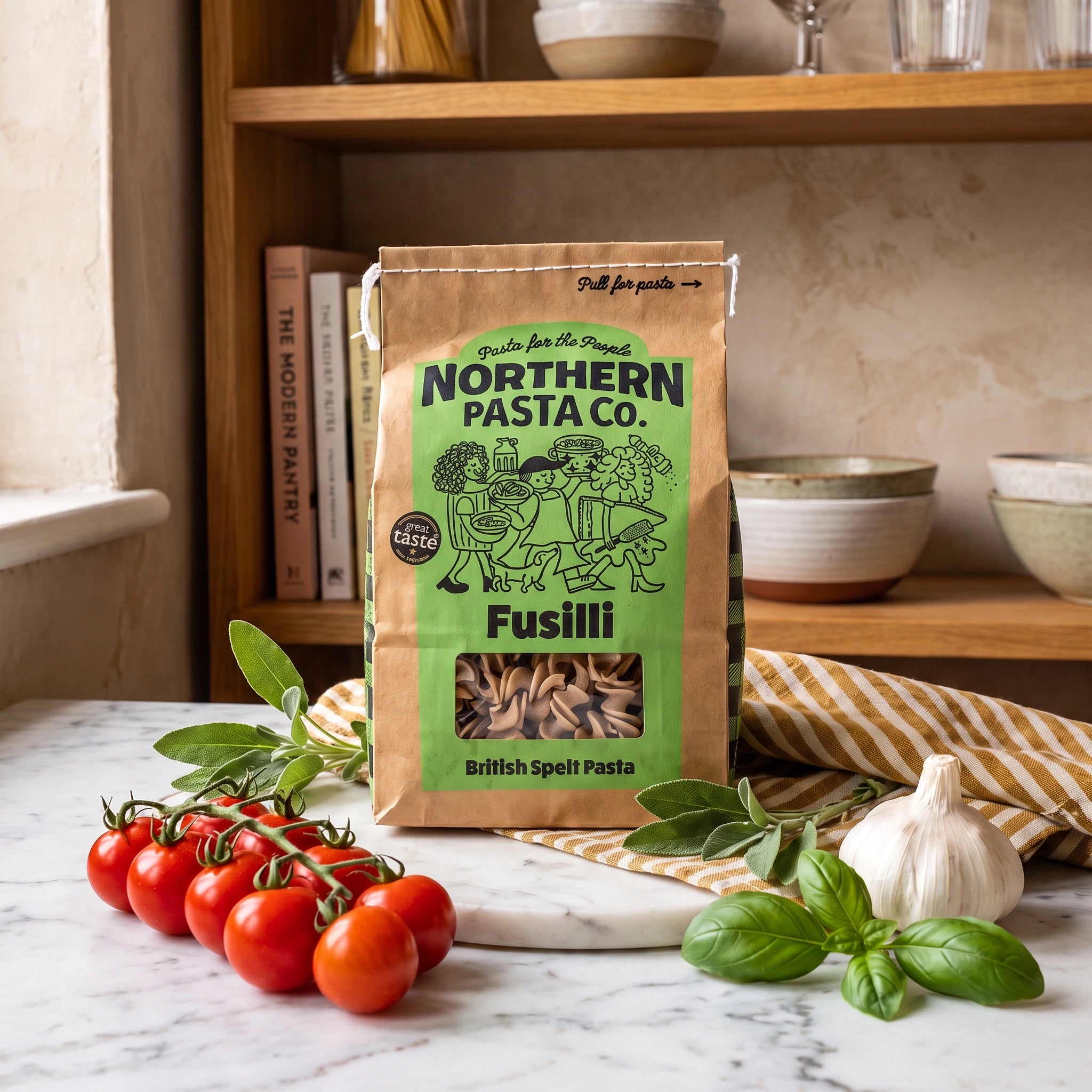 Northern Pasta Co. British Spelt Fusilli bag in a rustic kitchen with tomatoes, garlic and fresh herbs