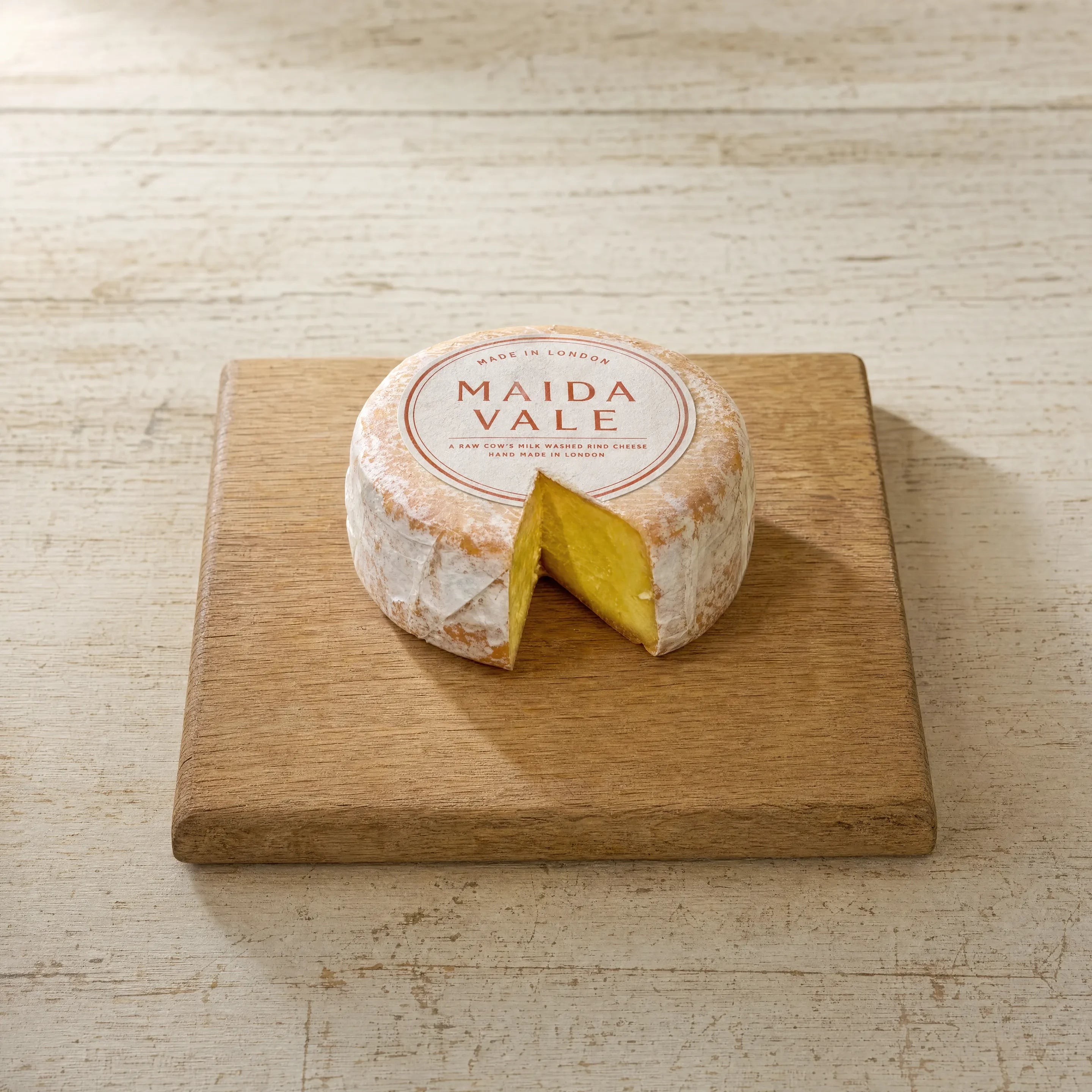 Maida Vale washed-rind cheese on an oak board, English cheesemonger counter