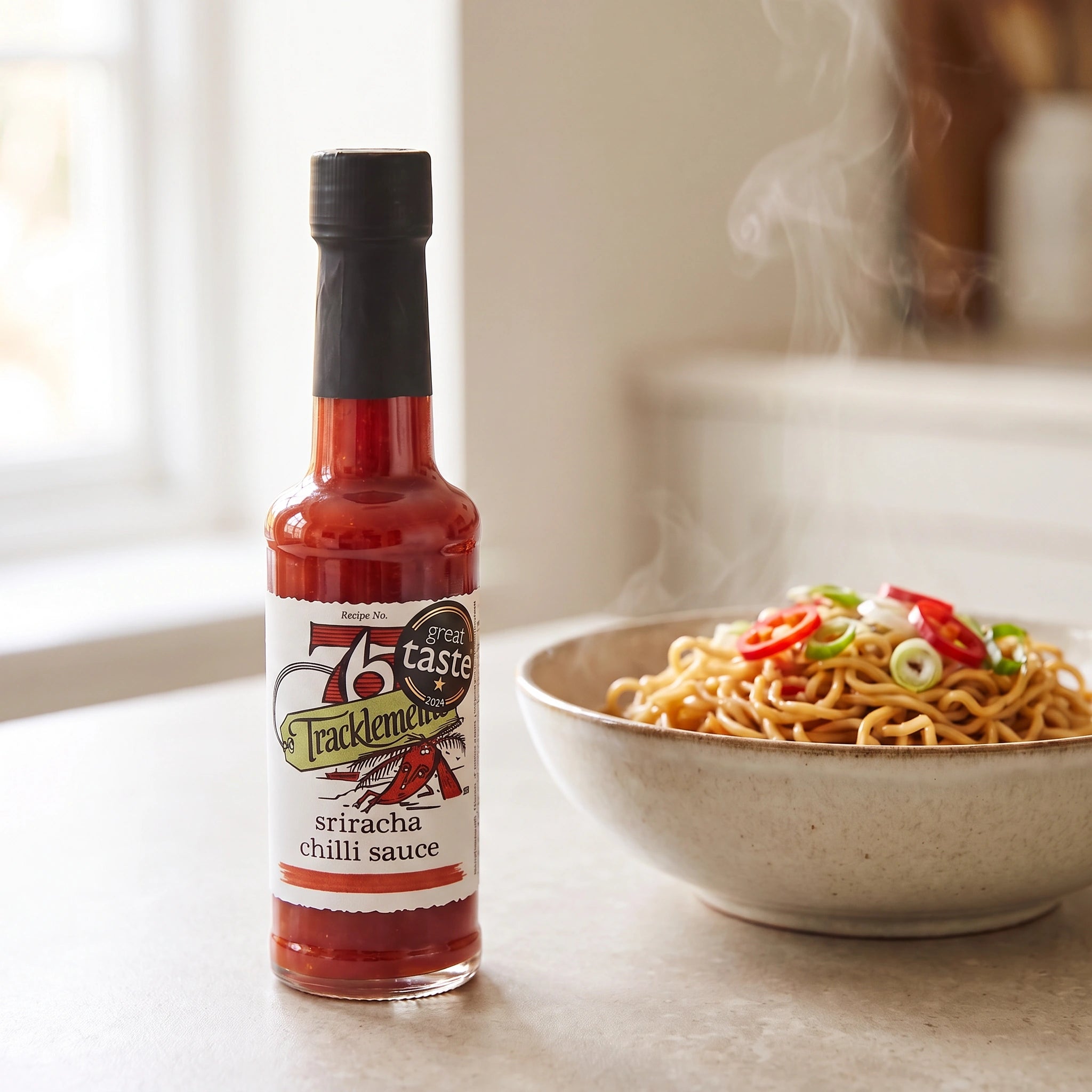 Tracklements Sriracha Chilli Sauce bottle with a bowl of noodles