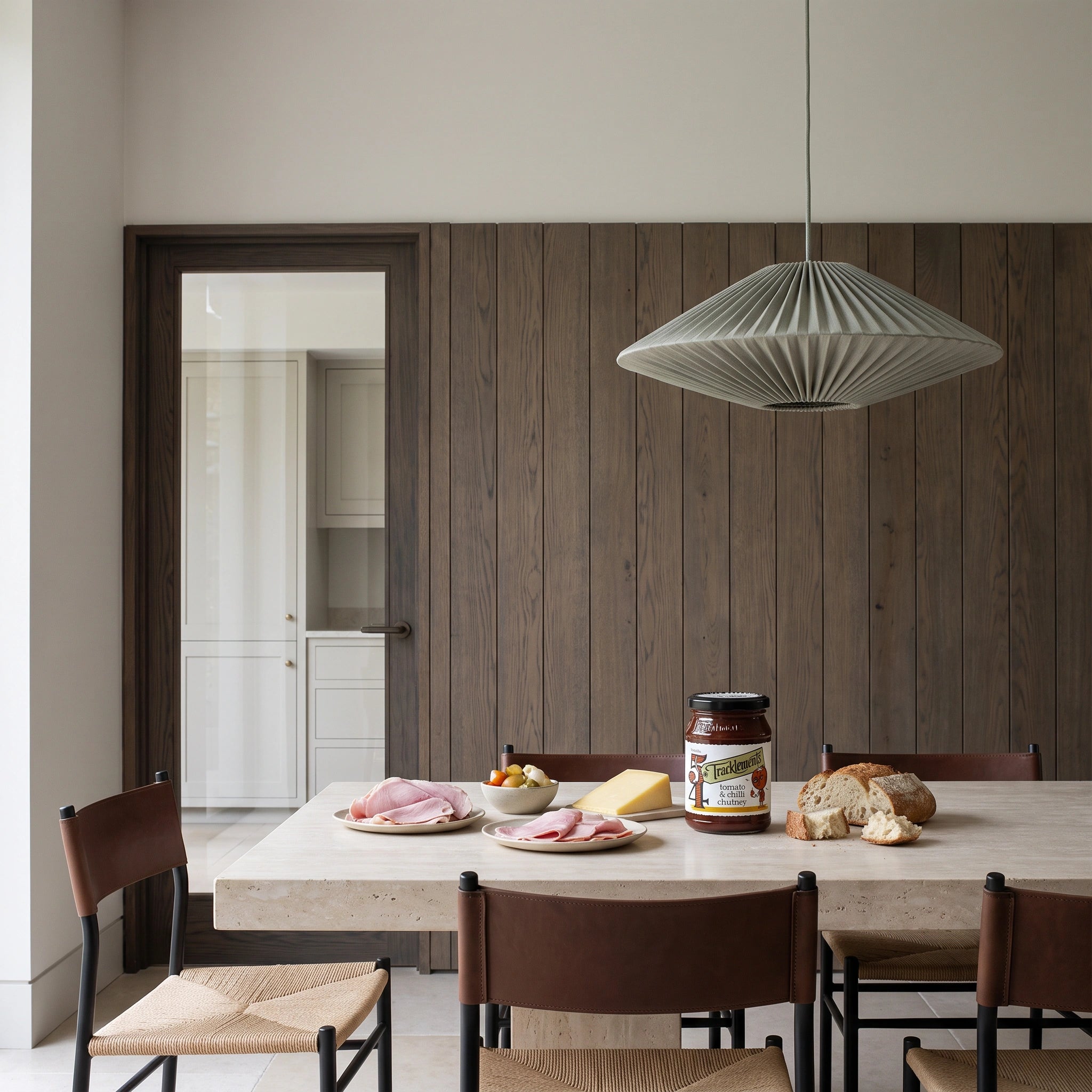 Tracklements Tomato & Chilli Chutney jar in a minimalist stone dining setting with a ploughman's spread