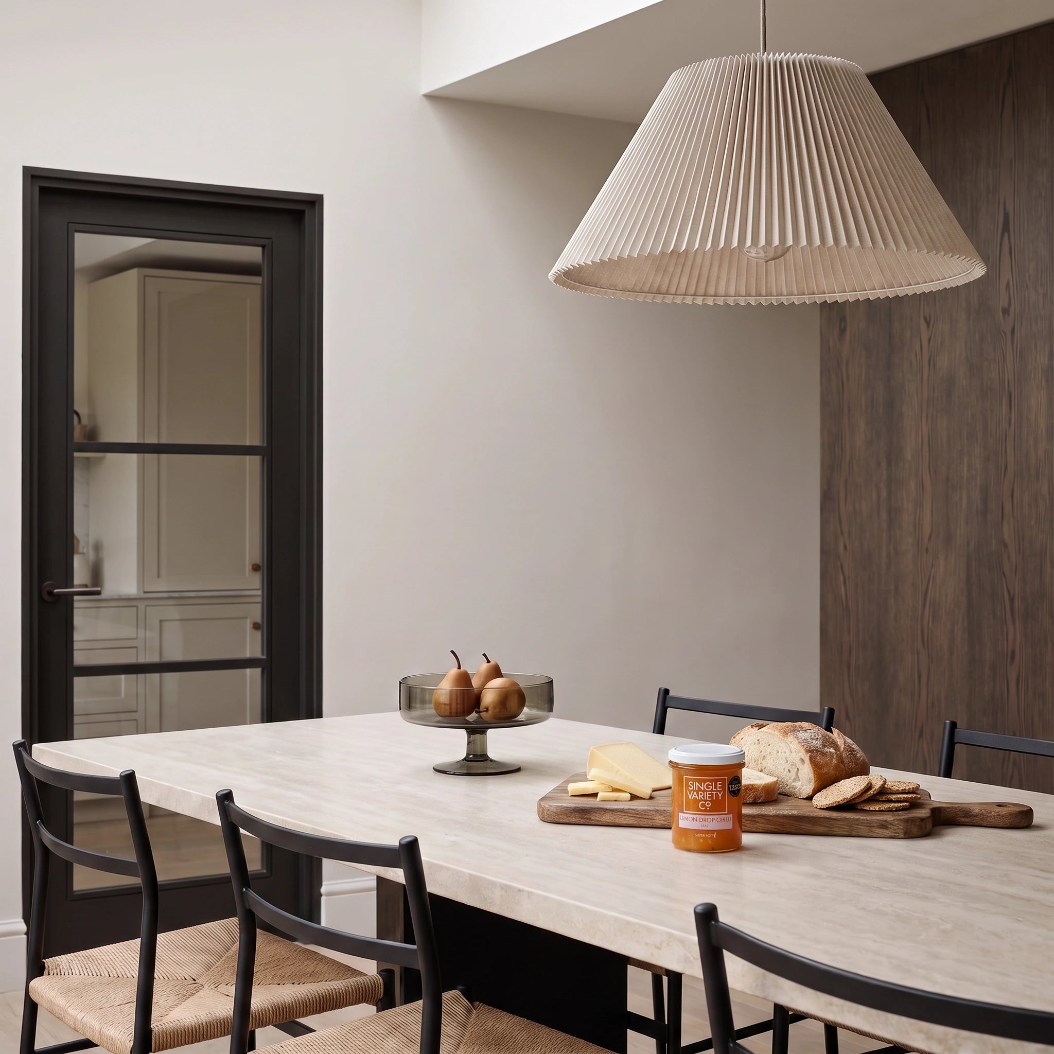 Single Variety Co. Lemon Drop Chilli Jam jar in a minimalist stone dining setting with cheese and bread