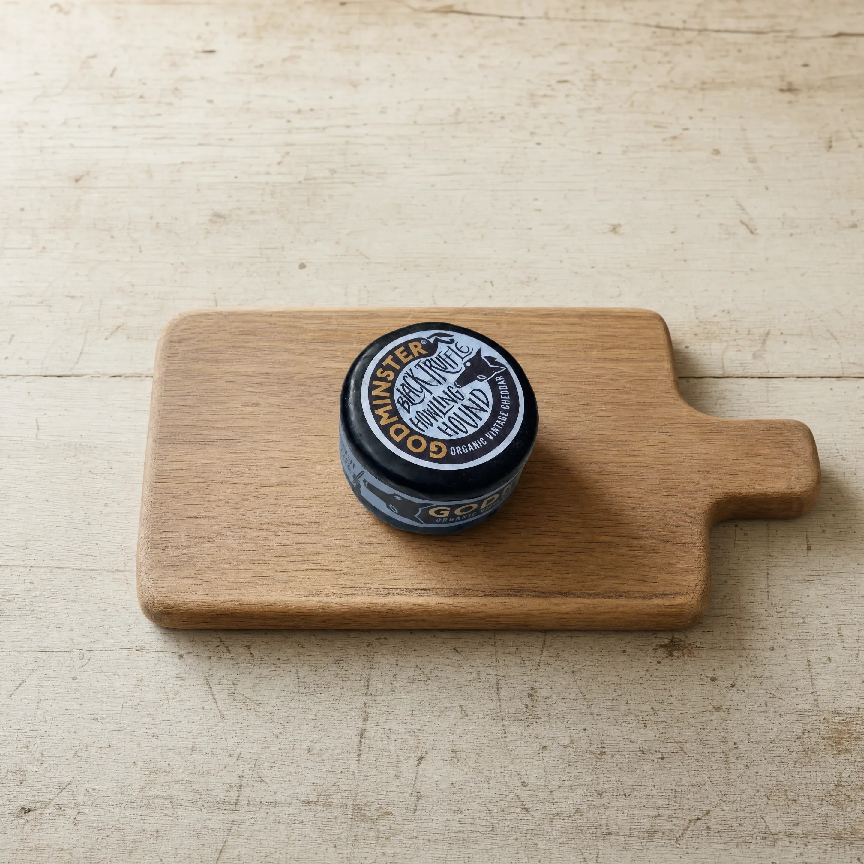 Godminster Black Truffle organic cheddar on an oak board, English cheesemonger counter