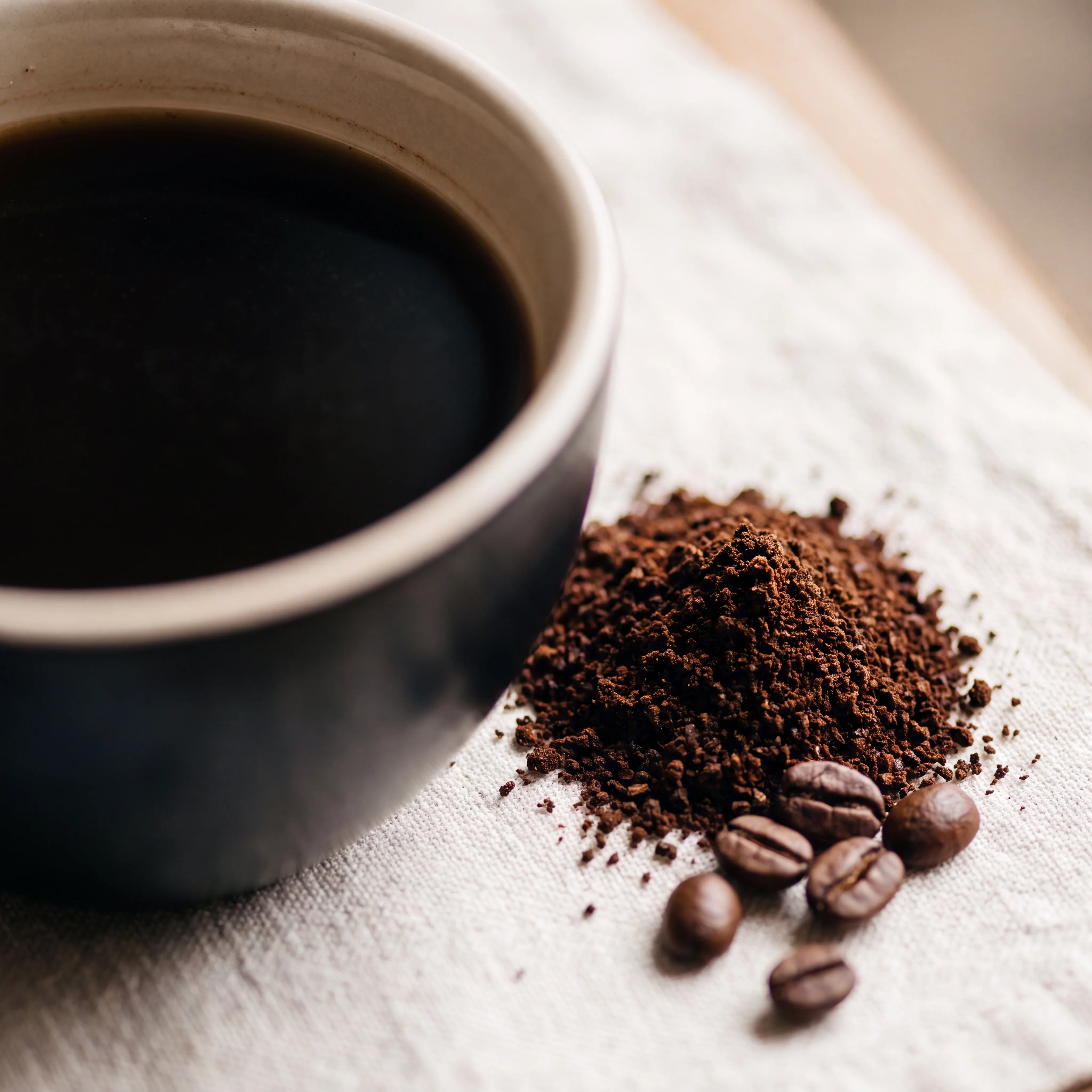Cup of very strong dark coffee with dark ground coffee and beans
