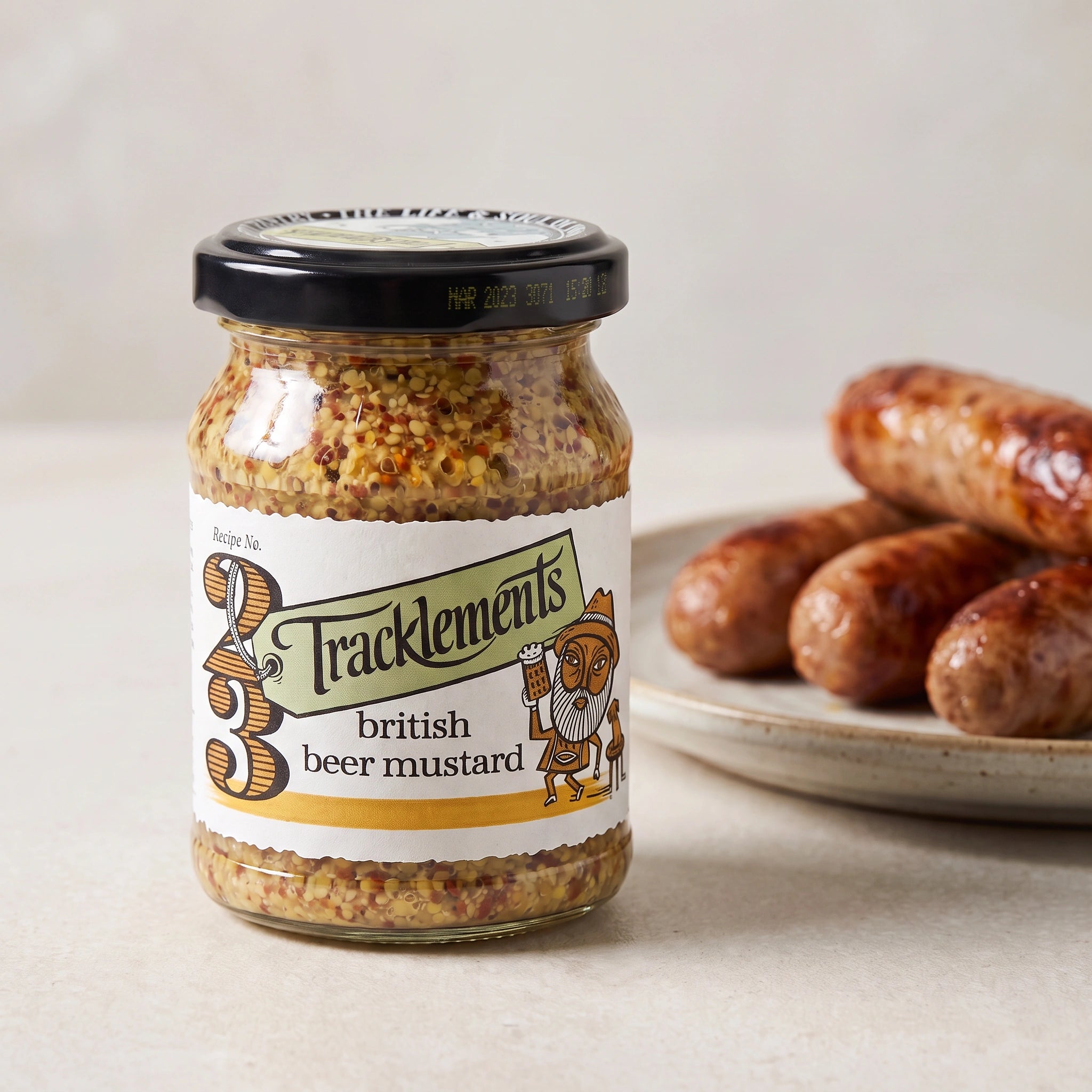 Tracklements British Beer Mustard jar with a plate of sausages