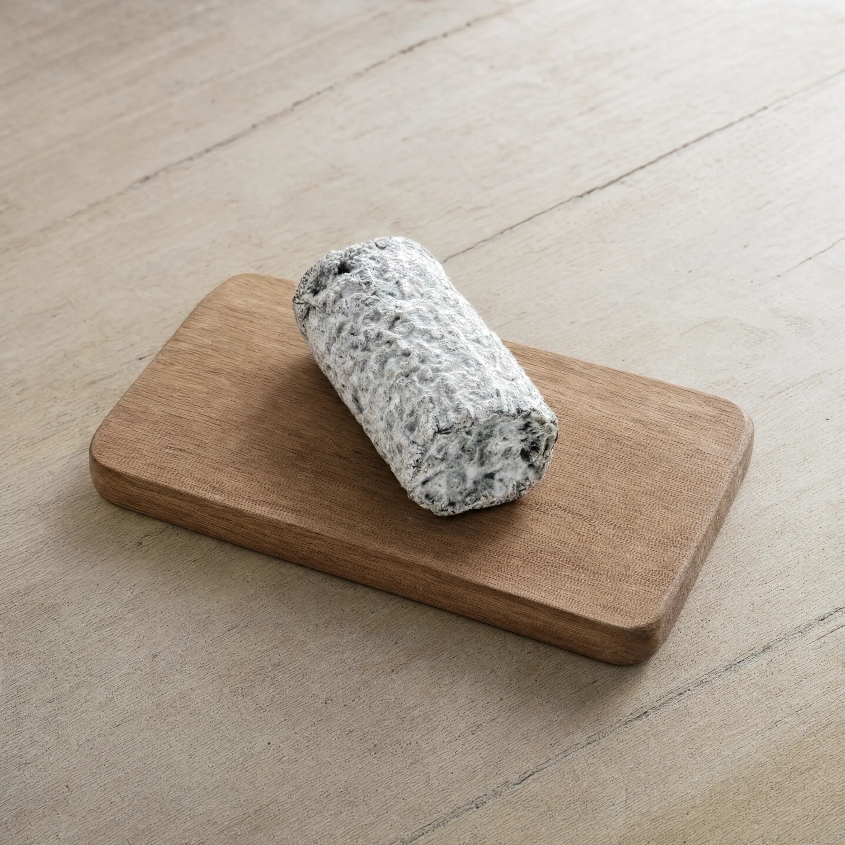 White Lake Driftwood ashed goat log on an oak board, English cheesemonger counter