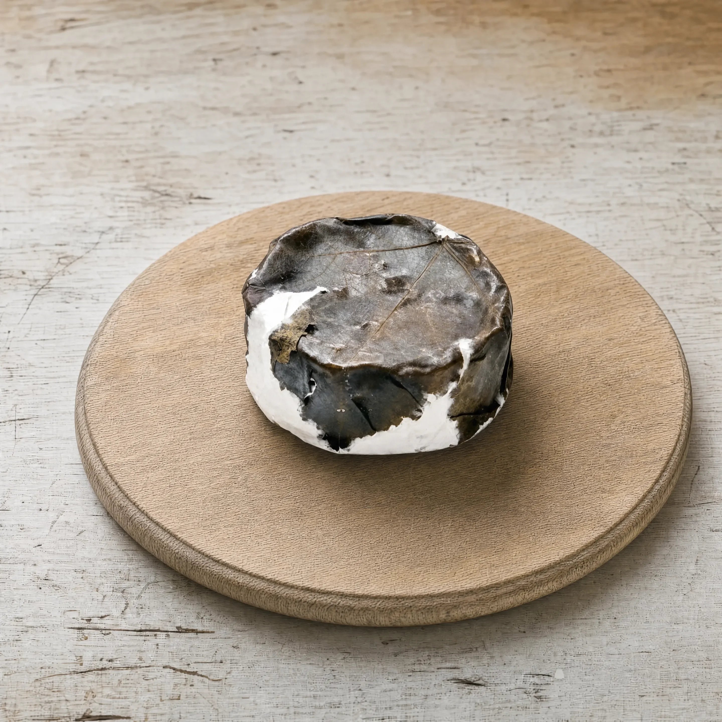Eve goats' cheese in vine leaf on an oak board, English cheesemonger counter