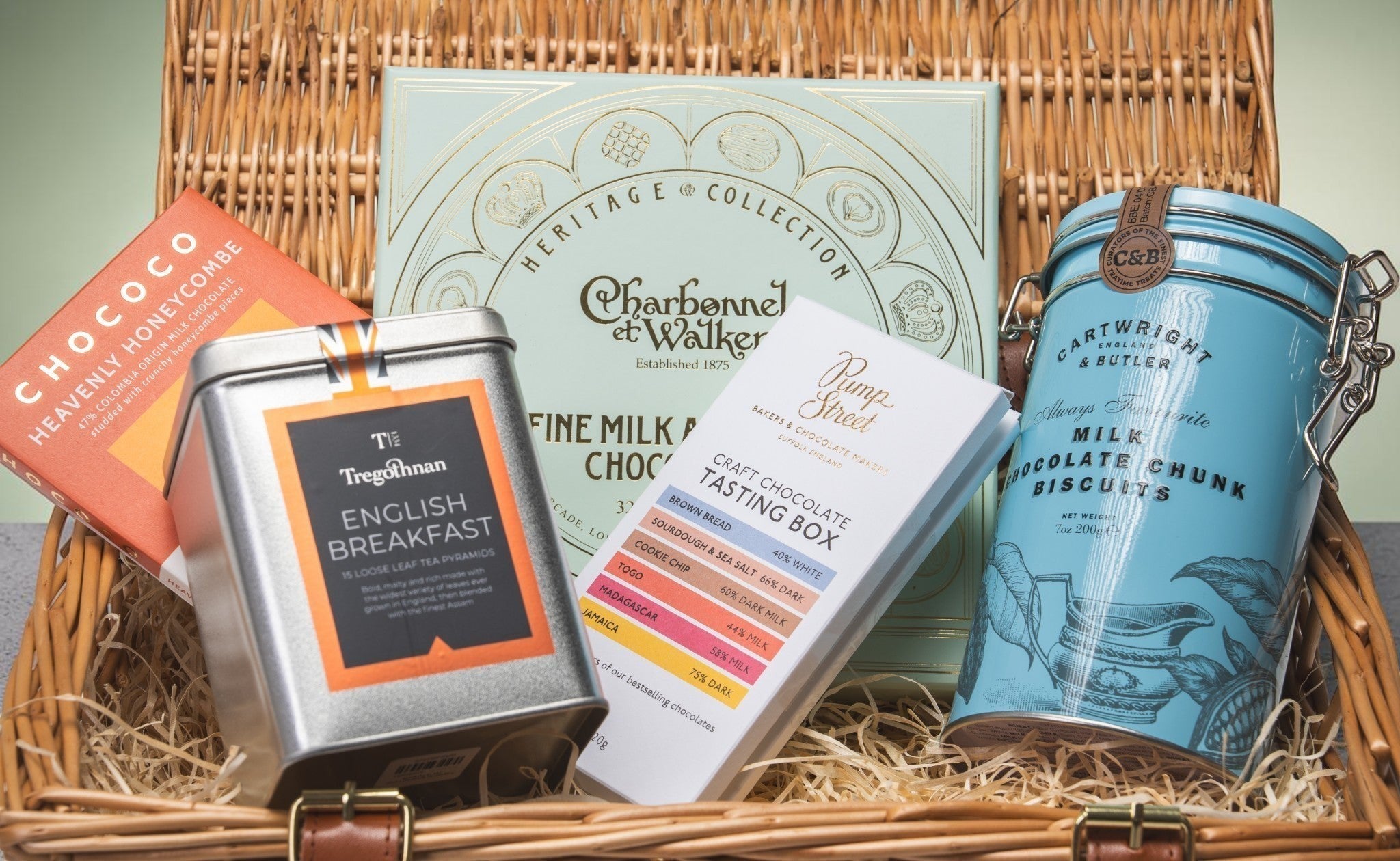 Made In England Artisan Chocolate and Tea Gift Hamper with assorted chocolates, biscuits, and English Breakfast tea in a woven basket.