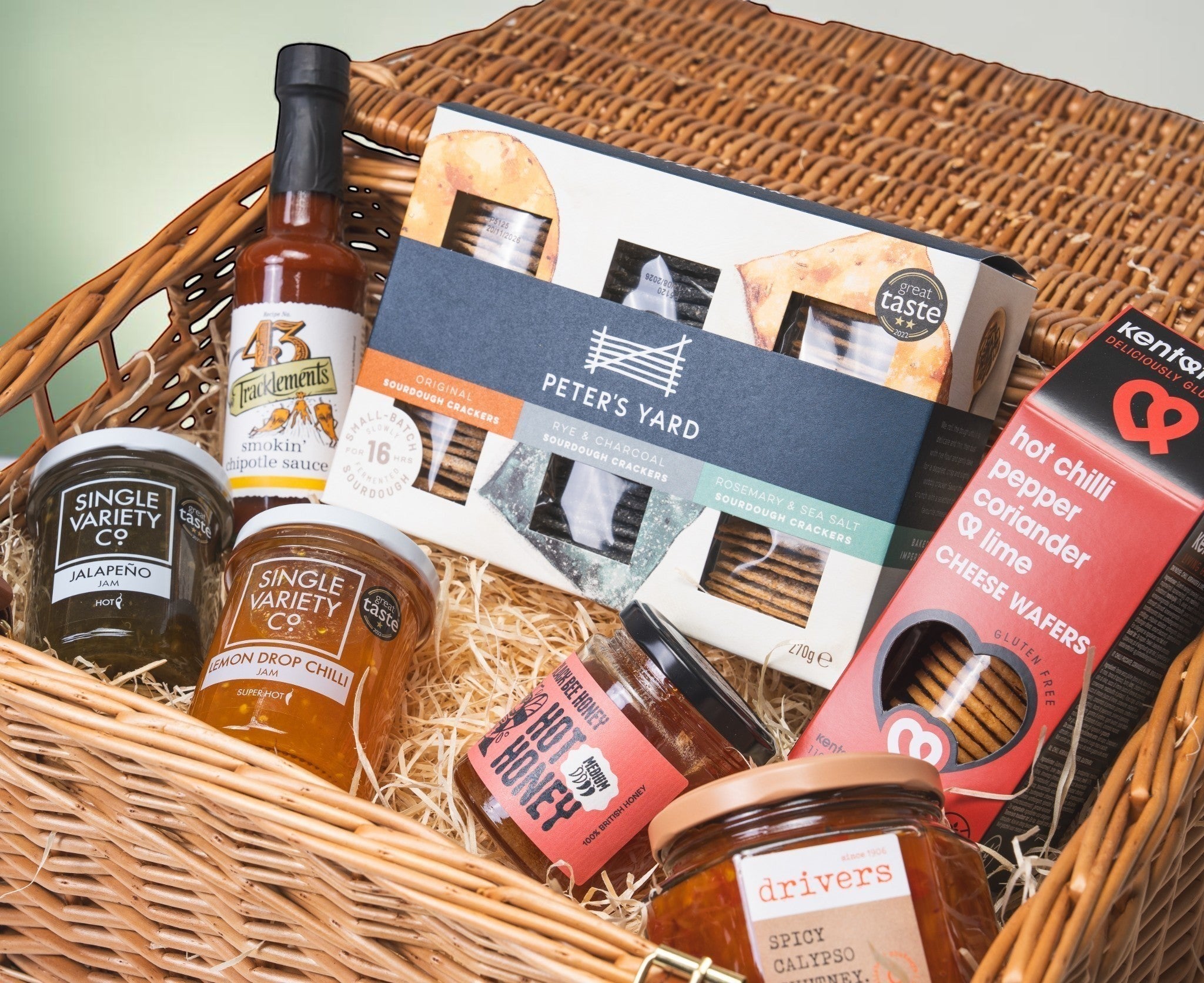 Made In England Firecracker Pantry gift hamper with jalapeño jam, lemon drop chilli jam, chipotle sauce, hot honey, chutney, cheese wafers, and crackers.