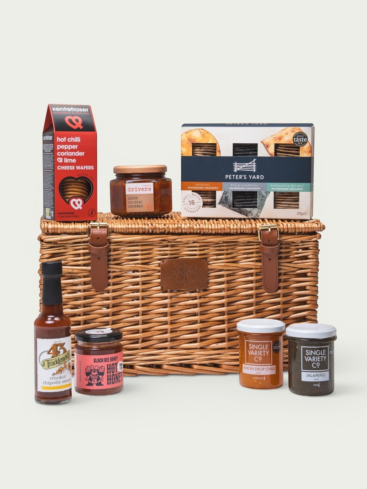 Made In England Firecracker Pantry hamper with hot sauces, jams, crackers, and chutney in a wicker basket.