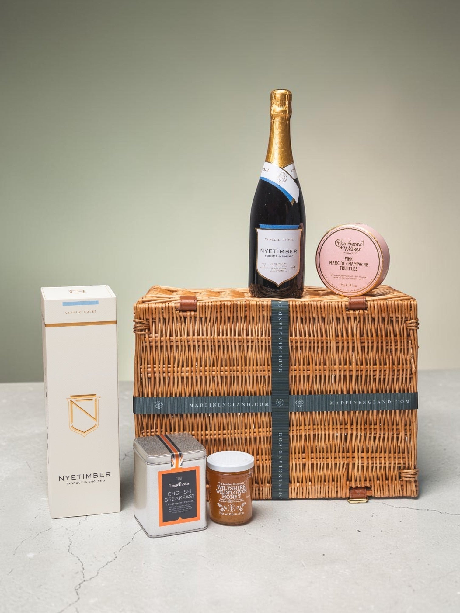 Made In England luxury picnic hamper with sparkling wine, English breakfast tea, wild honey, and truffles in a woven wicker basket.