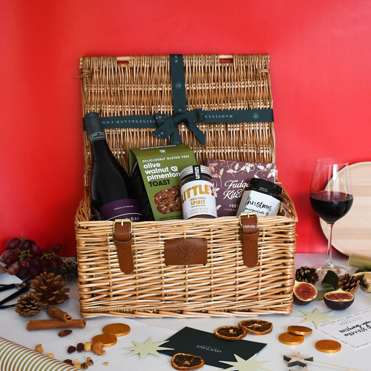 The Pinot Noir Christmas Hamper against a red background with a glass of red wine